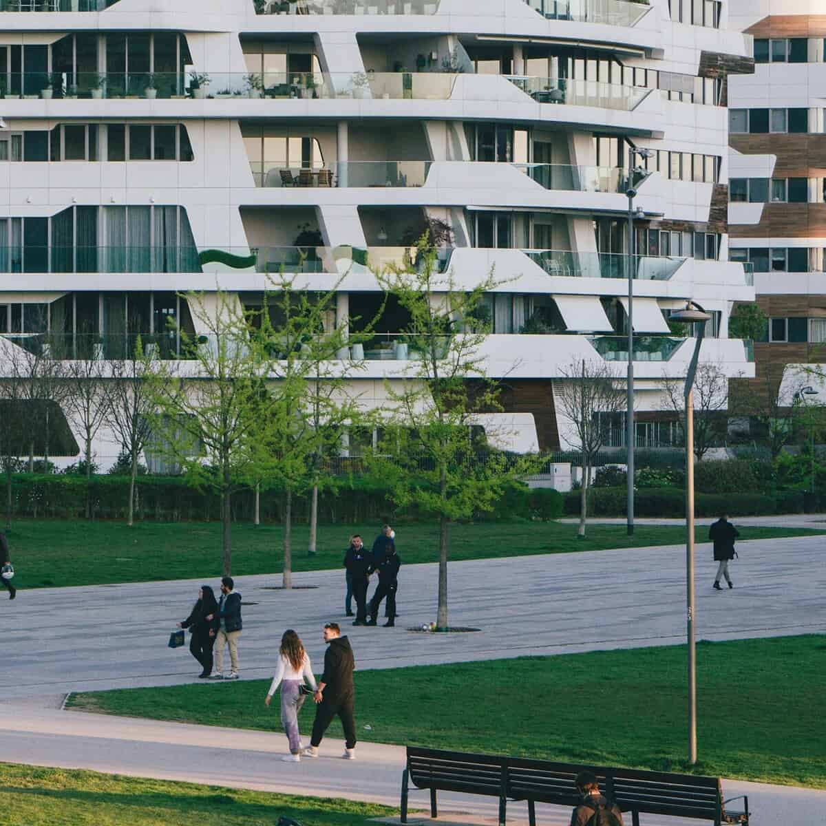 A modern street and a city park with families walking around.