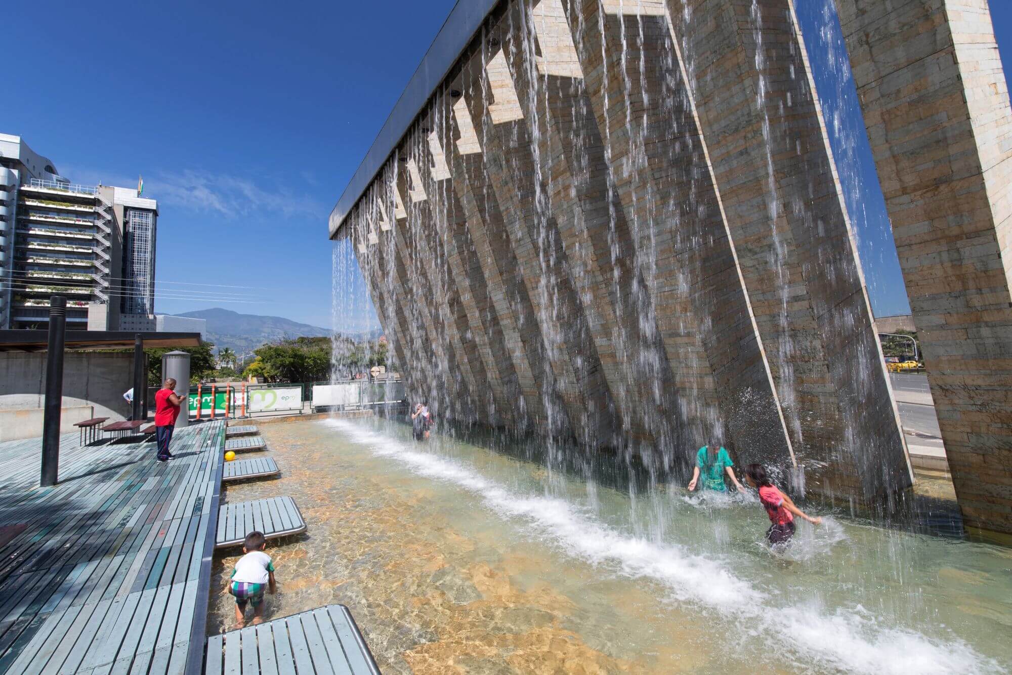 View of Barefoot Park (Parque de los Pies Descalzos) Medellin, Colombia. people splashing in a fountain on a summer day