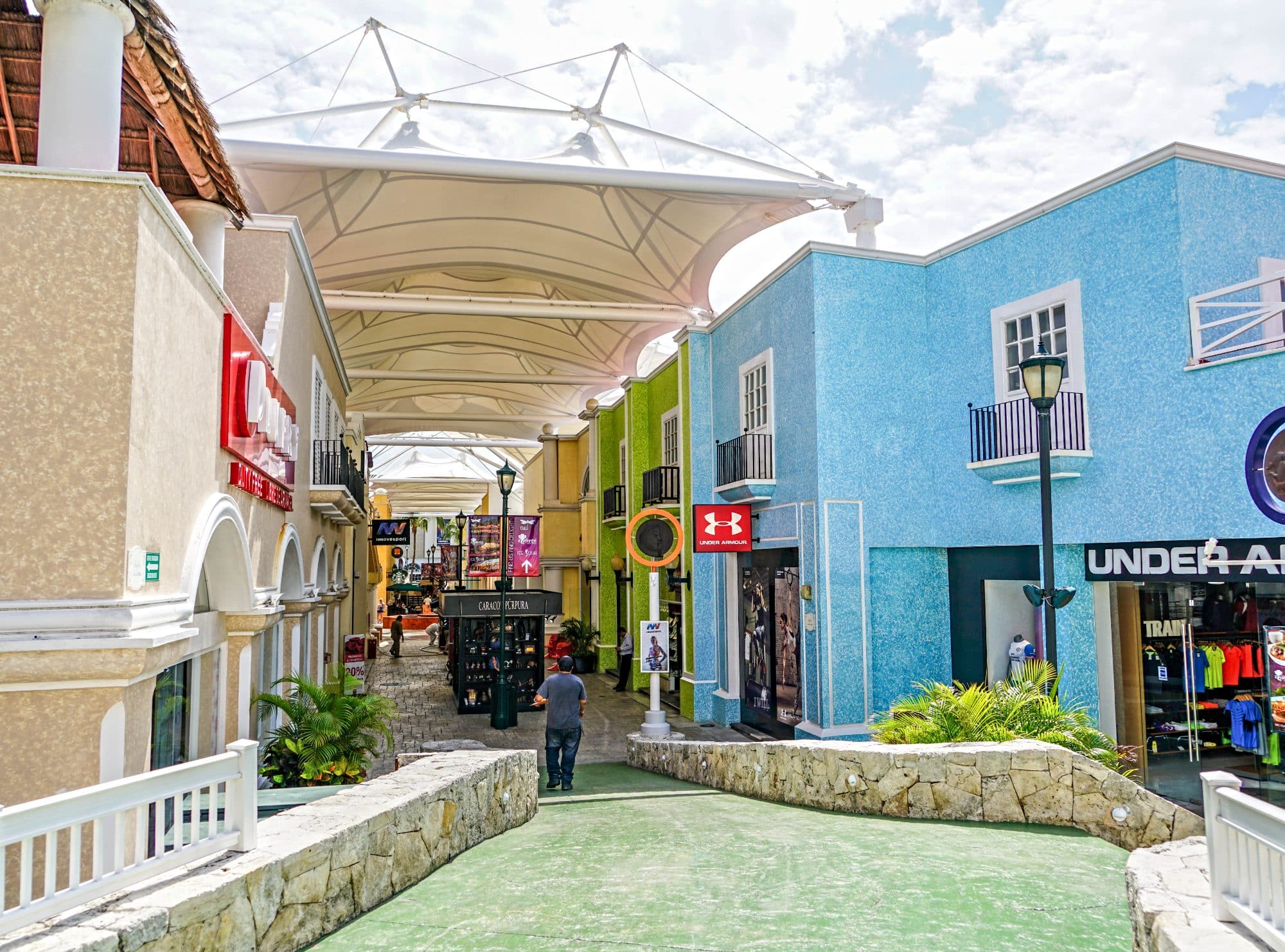 A colorful narrow pedestrianized street in Cancun with shops both sides and shades keeping the sun away