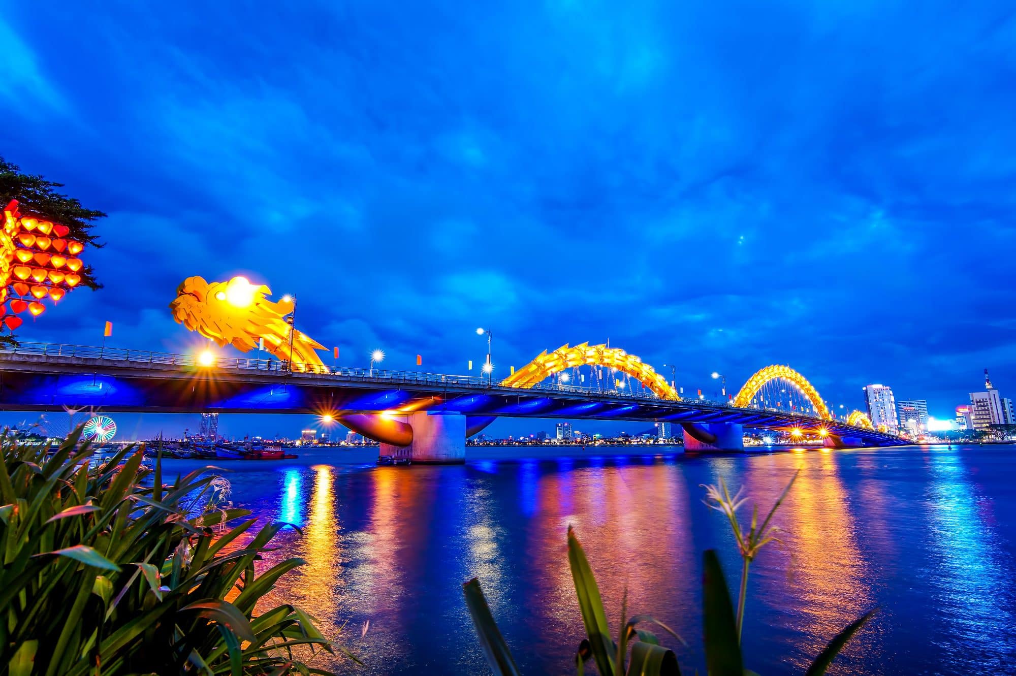 The Dragon Bridge of Da Nang, Vietnam at night - a brughtly lit bridge and reflections in the water