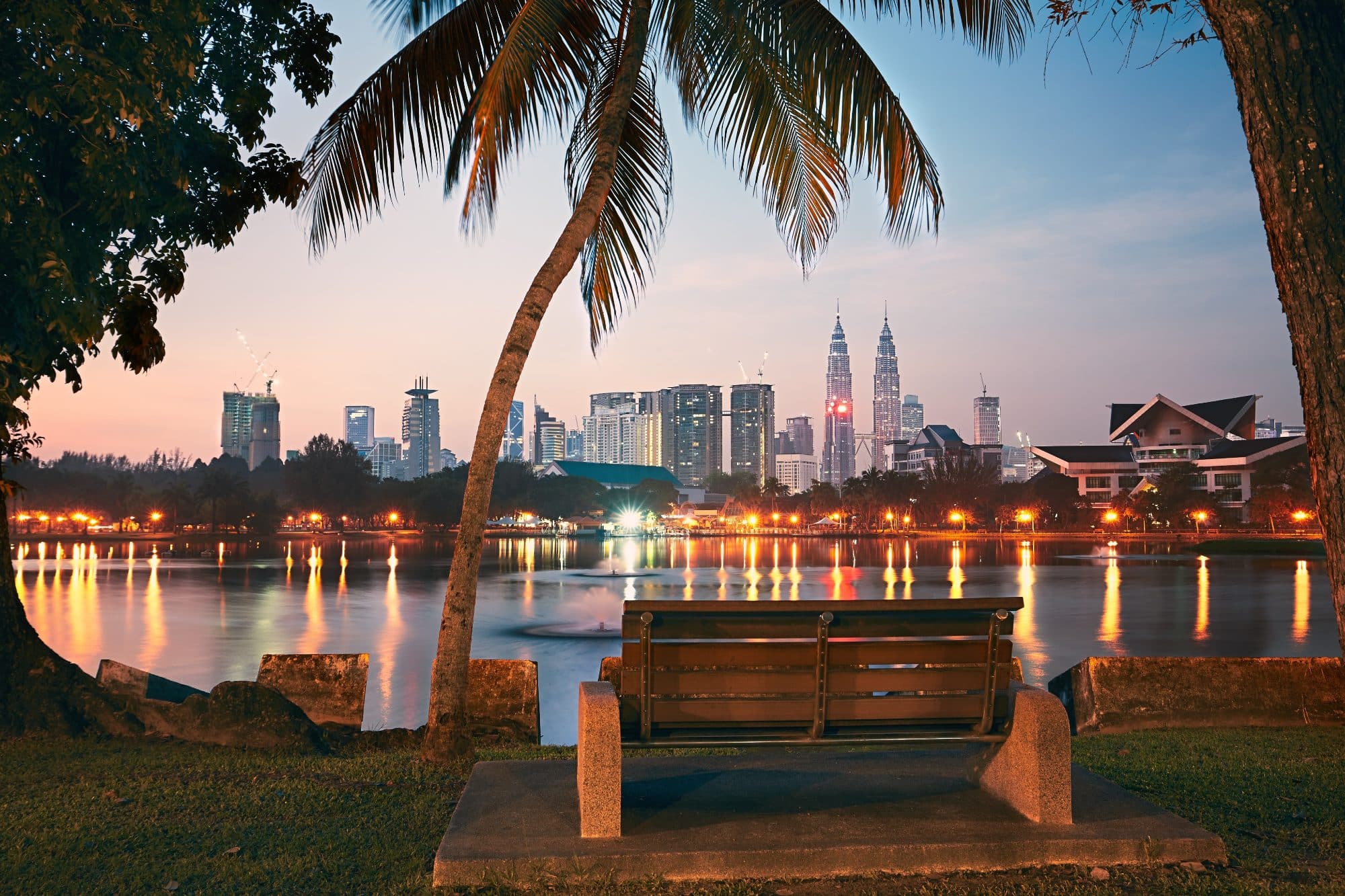 Kuala Lumpur at night - a bench on the waterfront with a cityscape view and city lights reflecting in the water
