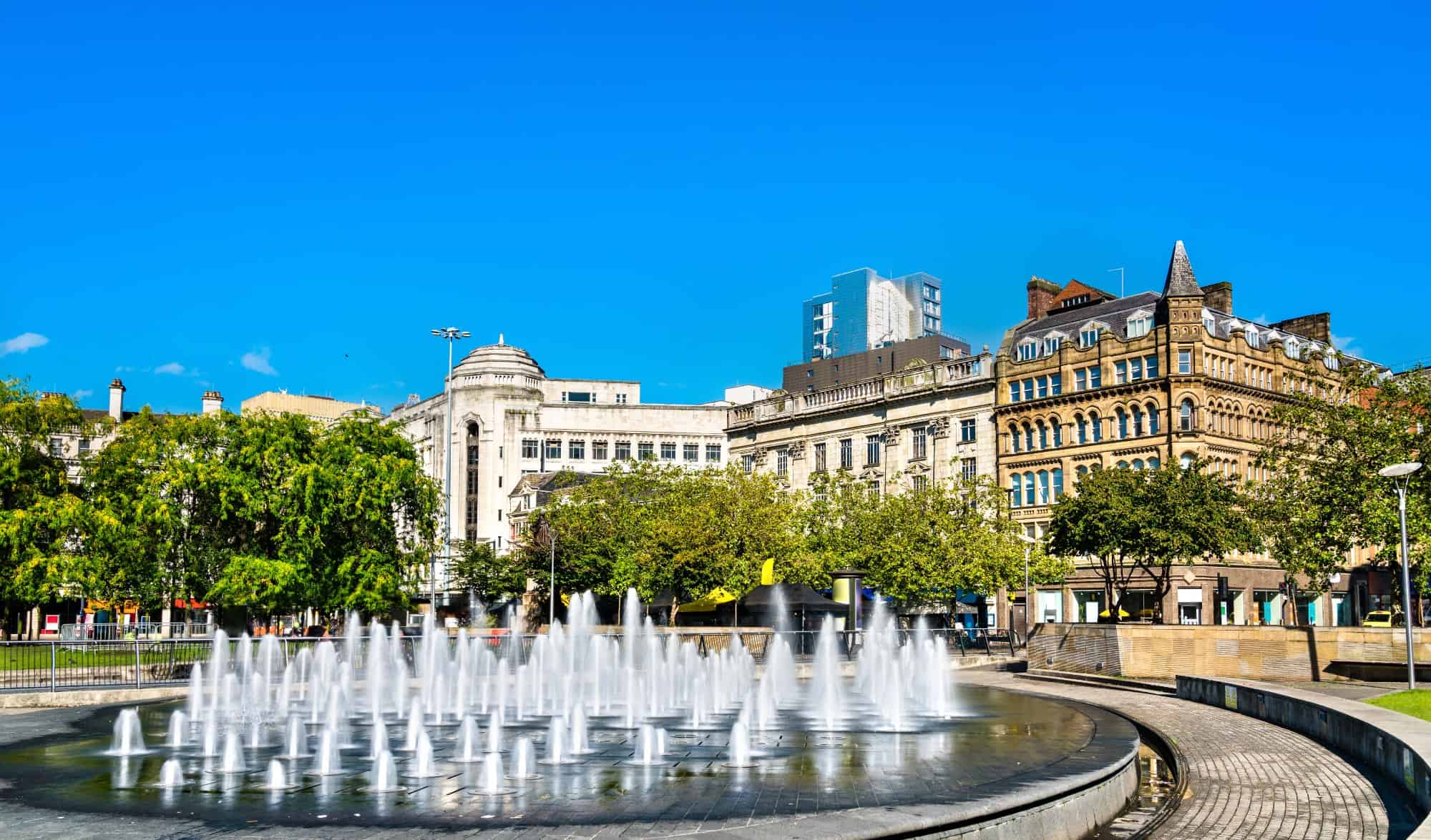Manchester Piccadilly Gardens - a view of a city square and a fountain on a sunny day.