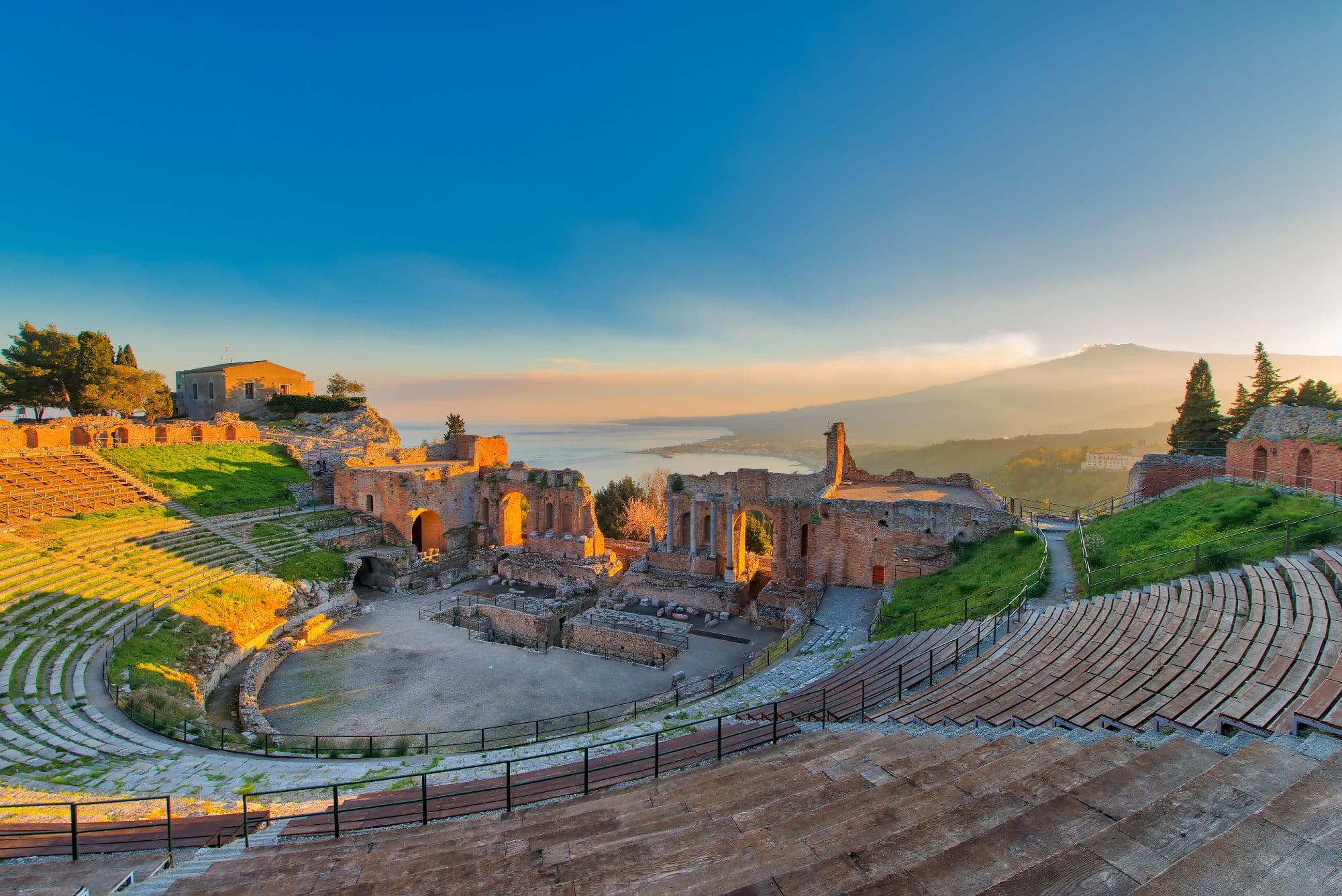 Ancient theatre of Taormina with Etna erupting volcano at sunset