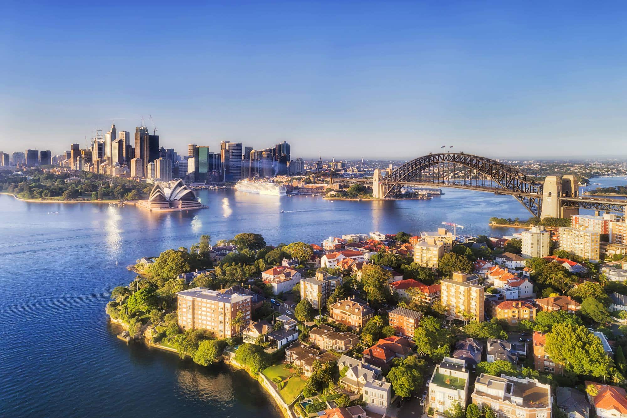 The Sydney Harbour Bridge, Sydney Opera House in the background, and residential areas of Sydney