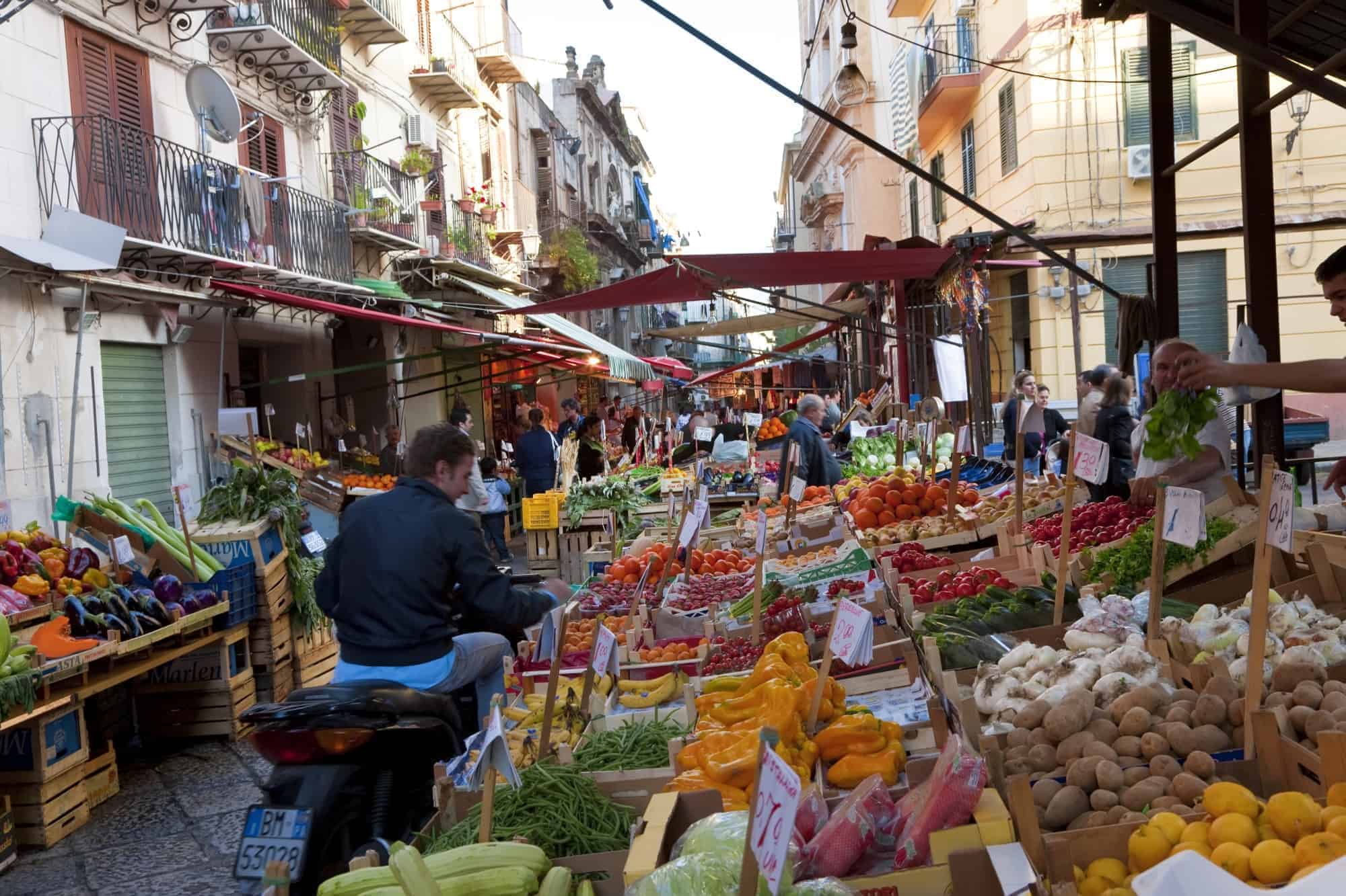 A busy street market in Palermo with stalls full of fresh produce