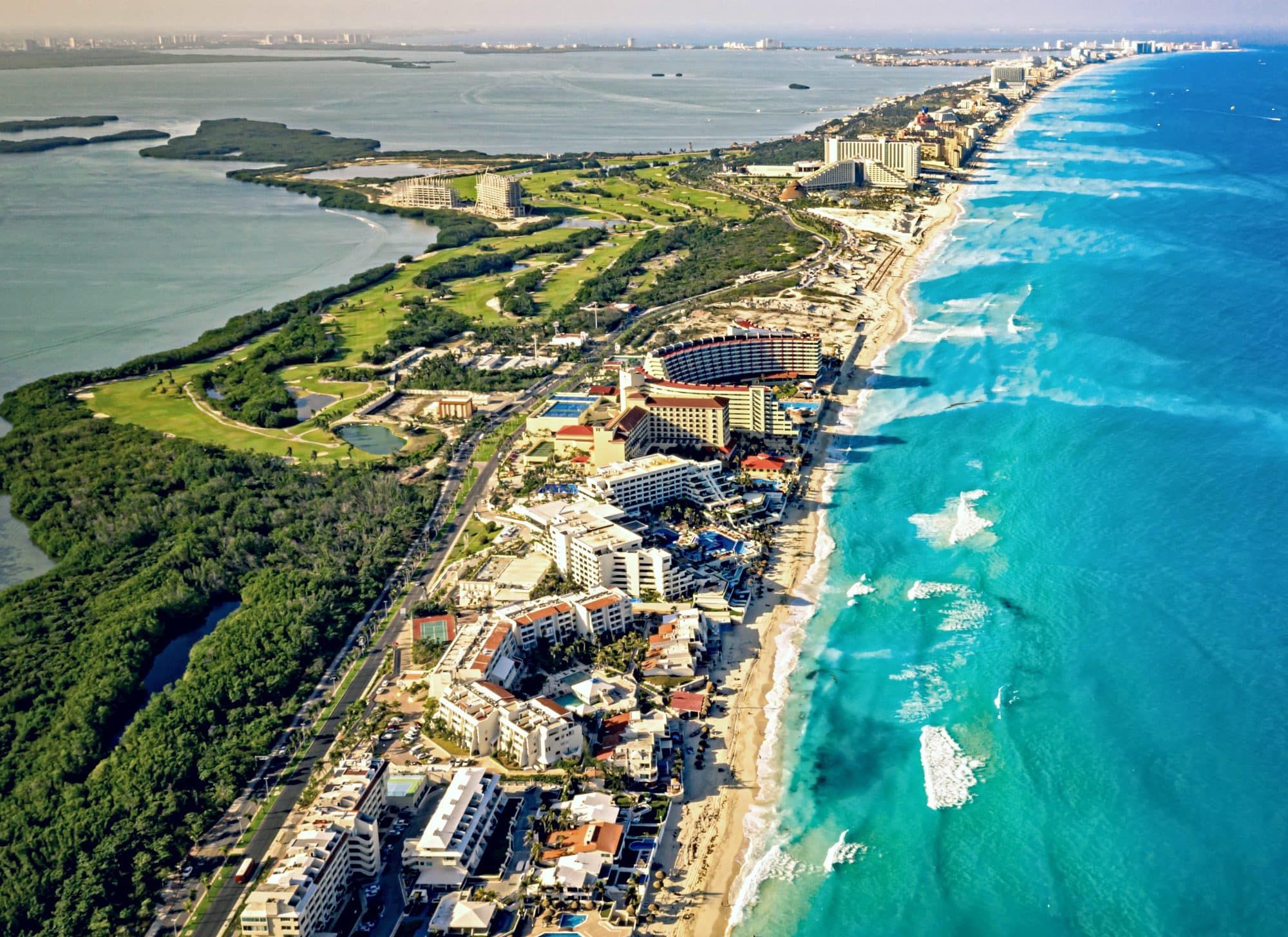 A drone view of the long piece of land of the Hotel Zone in Cancun with lovely andy beaches stretching along one side.